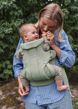 Parent carrying baby in the BabyBjorn Baby Carrier Hold, light green brushed woven